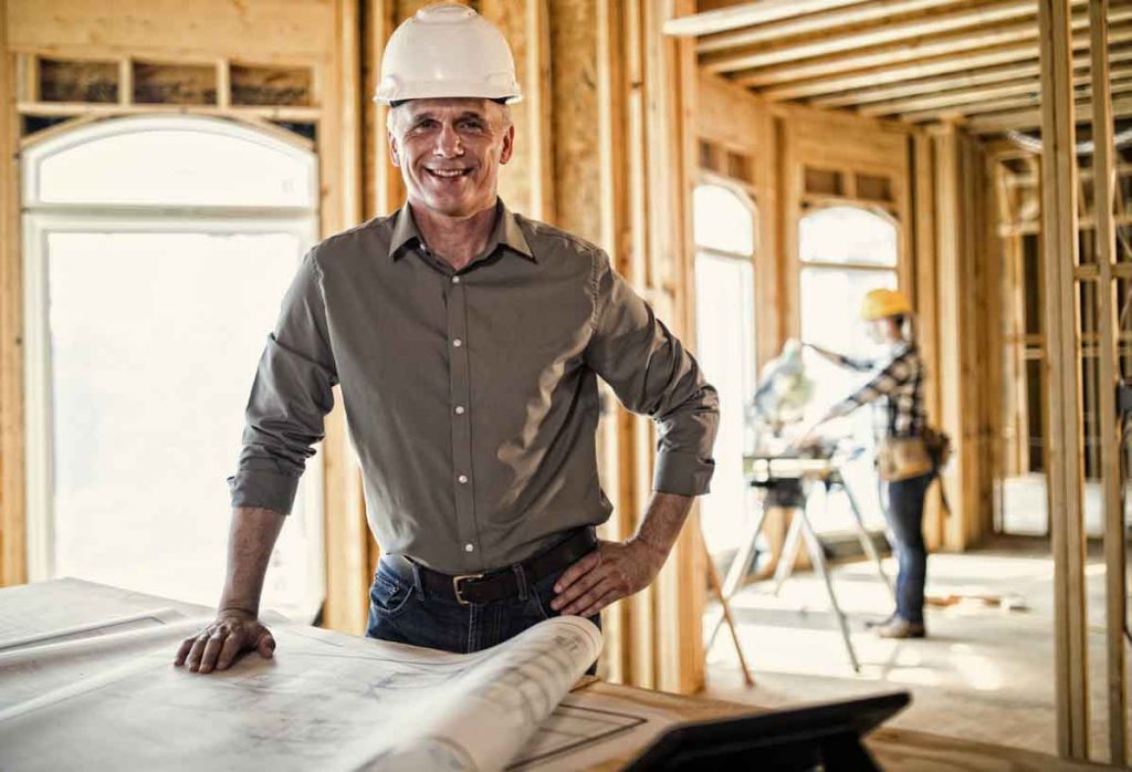 Architect looking over blueprints at home construction site.